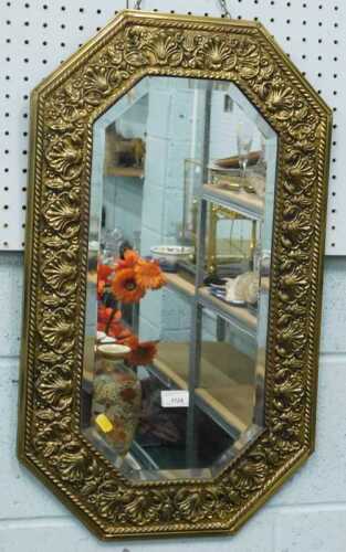 A brass hanging mirror, with bevelled glass and elaborate surround.