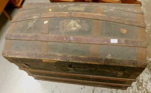 A late 19thC leather bound domed trunk, with part wooden banding and some luggage labels.