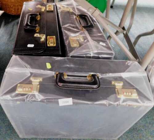 V - Three large leatherette and brass brief or flight cases, with combination locks. Note: VAT is...