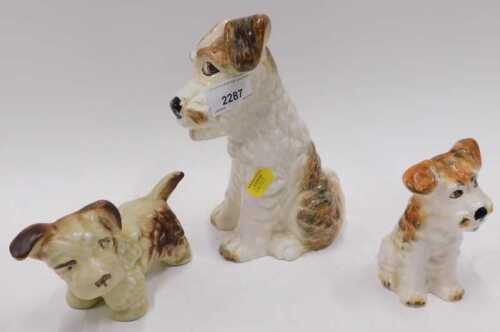 A Sylvac model of a terrier, brown and white glaze, together with two other pottery dogs.