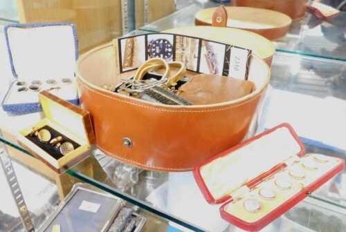 A leather shirt collar box, containing various collar studs, cufflinks, elasticated armbands,...