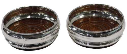 A pair of Queen Elizabeth II silver and oak lined coasters, of bellied form, with rope twist...