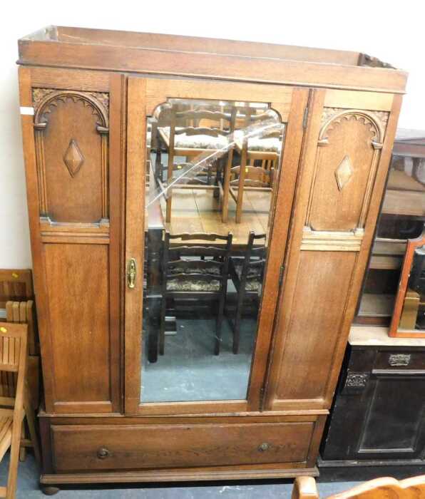 An early 20thC oak wardrobe, the top with a moulded cornice above a single bevelled mirror door,...