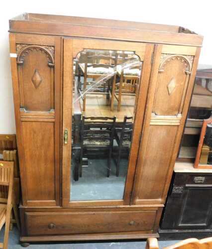 An early 20thC oak wardrobe, the top with a moulded cornice above a single bevelled mirror door,...