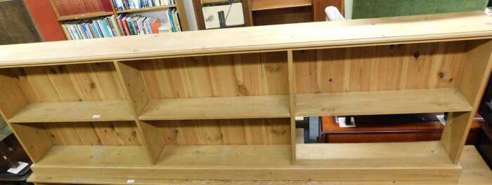 A pine open bookcase, with six sections, one section lacking panelled back, 82cm high, 250cm...