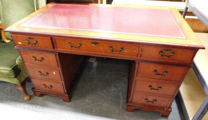 A pedestal desk, the top inset with a maroon tooled leather panel, above an arrangement of nine...