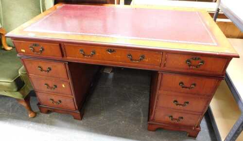 A pedestal desk, the top inset with a maroon tooled leather panel, above an arrangement of nine...