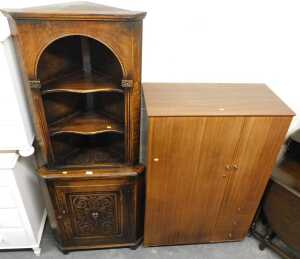 An oak standing corner cabinet, the top with two shaped shelves, above a profusely carved door,...