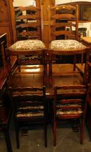 An oak draw leaf table, together with six ladderback chairs, each with an overstuffed tapestry...