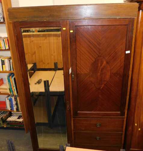 An Edwardian mahogany and walnut inlaid compactum wardrobe, with a mirrored glass door flanked...