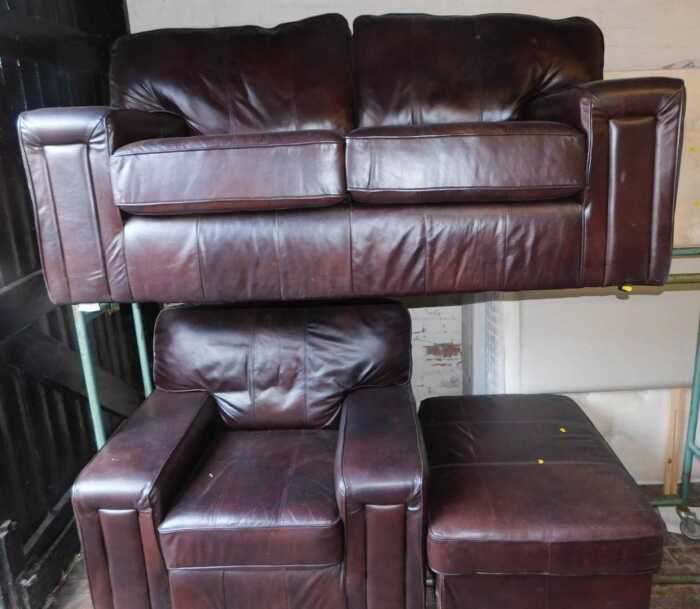 A brown leather sofa suite, comprising a two seater sofa, an armchair, and a footstool. (3)