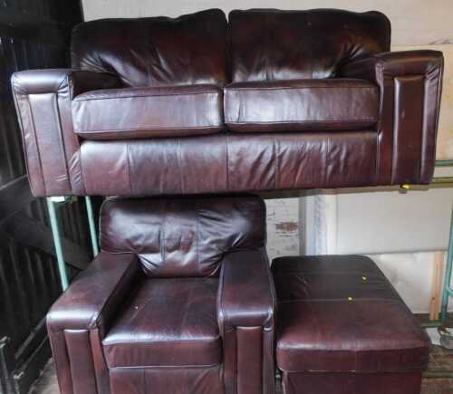 A brown leather sofa suite, comprising a two seater sofa, an armchair, and a footstool. (3)
