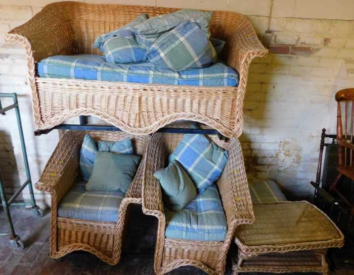 A wicker conservatory suite, comprising two seater sofa, two armchairs, and a table. The...