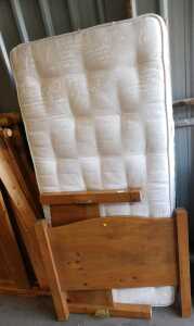 A pine single bed frame, together with a mattress, and a walnut wardrobe base.