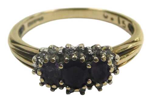 A 9ct gold and amethyst three stone ring, in a claw setting, with a surround of brilliant cut...