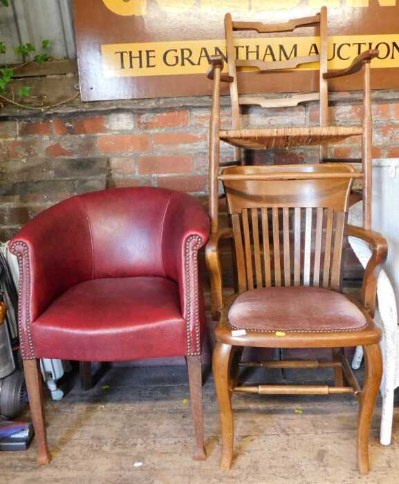An early 20thC oak chair, together with another with a rush seat, and a red faux leather...