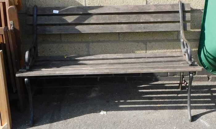 A garden bench, with cast metal end supports, and wooden slatted base.