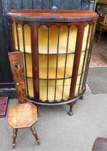 A mahogany bow front display cabinet, raised on ball and claw feet, together with a chair.