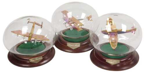 Three late 20thC Northumbrian glass sculptures of RAF planes, each under a glass dome, with a...