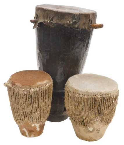 An African tribal drum, possibly Makonde, of carved wood and hide bound, 40cm high, together...
