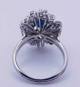 A sapphire and diamond ring, the oval cut sapphire in a tiered claw setting, framed by baguette... - 2