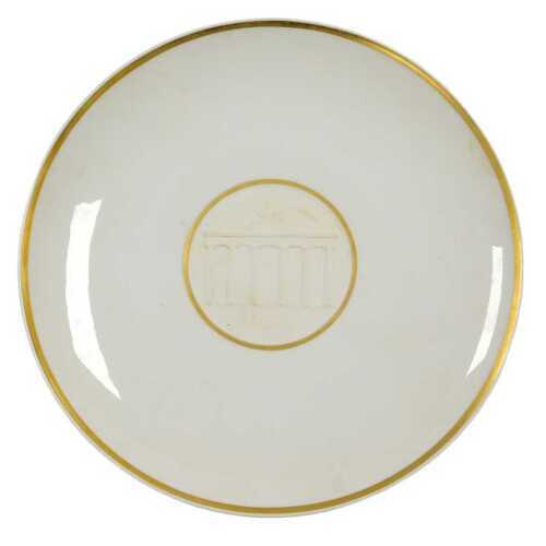 A Berlin bisque and white glazed porcelain plate, decorated centrally with the Brandenburg Gate,...