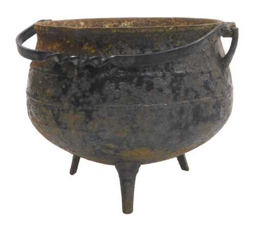 A late 19thC cast iron cauldron, with a swing handle, raised on tripod feet, 26cm high.