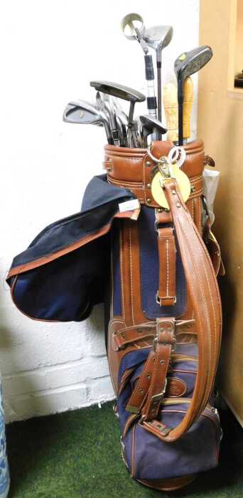 A leather and blue canvas golf caddy bag, containing various golf clubs, to include a sand wedge,...