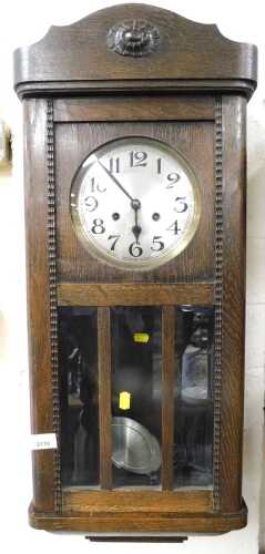 An oak cased wall clock, the circular silvered dial bearing Arabic numerals, with an eight day...