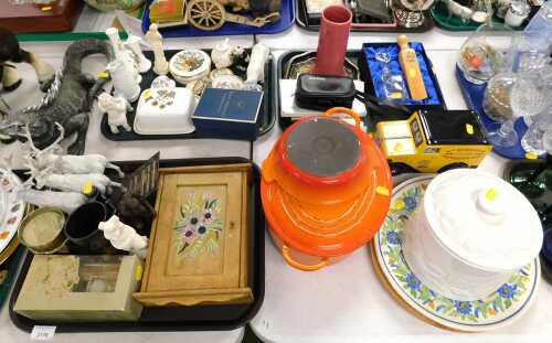 An orange Le Creuset cast iron oval lidded casserole dish, and a stoneware oven dish, together...