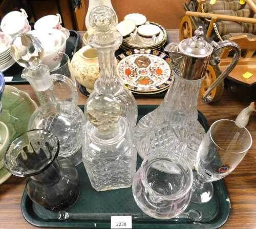 A cut and pink painted glass jug, a square section decanter and stopper, two further decanters...