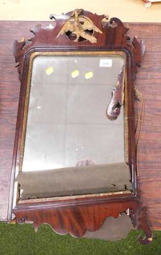A George V mahogany mirror, with scroll design to the top and a gilt bird inset in a circular...