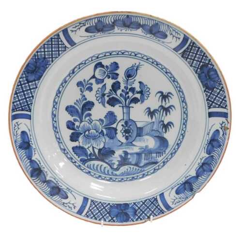 An 18thC Delftware charger, painted centrally with a vase of flowers, further flowers and bamboo,...
