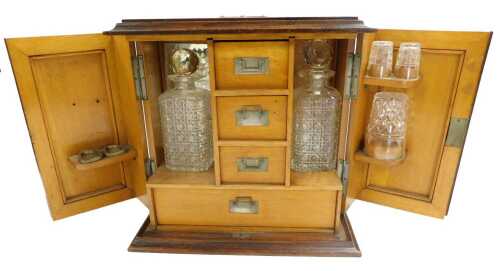 An early 20thC oak cased gentleman's drinks and smoking cabinet, the hinged doors opening to...