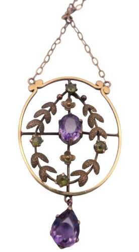 An Edwardian amethyst and peridot pendant, in an oval wreath and openwork frame design, on a...