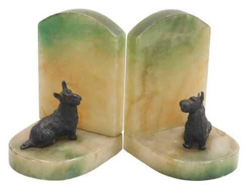 A pair of early 20thC onyx bookends, surmounted with cold painted figures of Terriers, 11.5cm high.