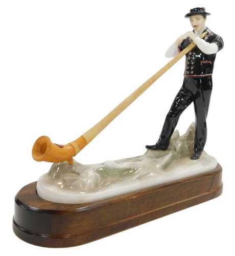 A Royal Worcester porcelain figure of a Swiss gentleman playing an alphorn, on a wooden base,...