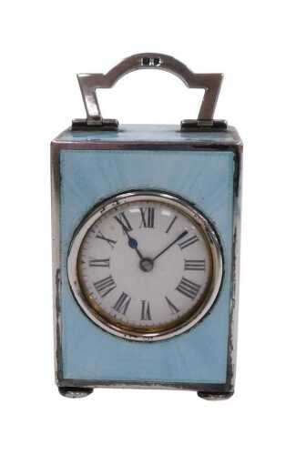 A George V silver and turquoise guilloche enamel travel clock, circular white enamel dial...