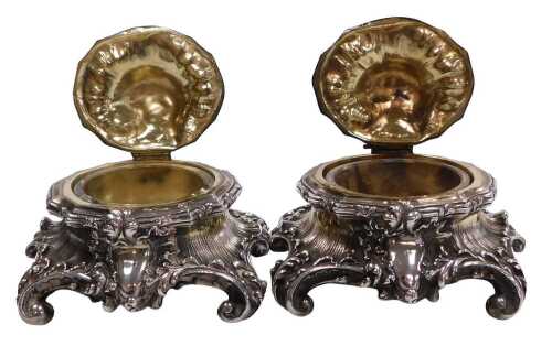 A pair of 19thC rococo style salts, with clear glass liners, with hinged lids, raised on four...