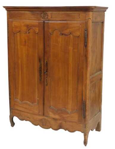 A French fruitwood armoire, the top with a moulded edge above a frieze, carved to the centre...