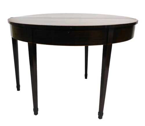 A George III mahogany fold over tea table, the demi lune shaped top with a boxwood strung and...