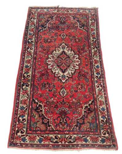 A Persian rug, with a central medallion, with cream border, on a red ground with brown and blue...