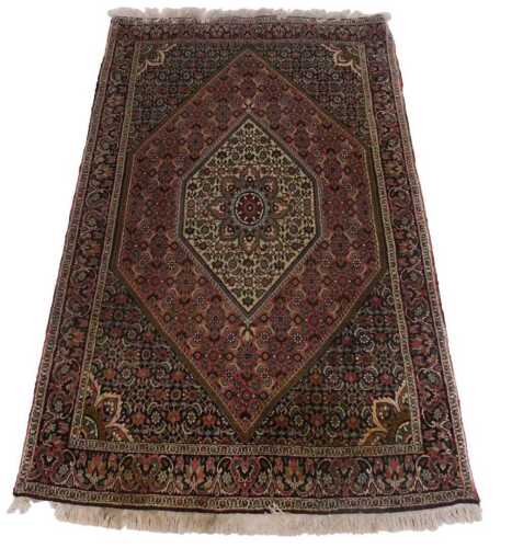A Persian rug, with a central medallion, mainly in green, on a cream ground, within dark pink...