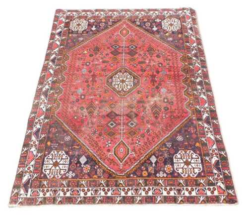 A Persian rug, with a central pole medallion, on a red ground, with deep navy spandrels, three...