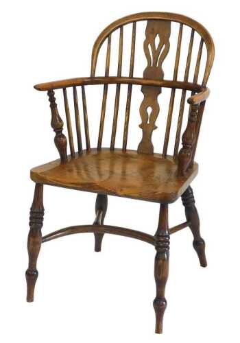 An ash and oak Windsor armchair, with a pierced back, solid seat, on turned legs with a...