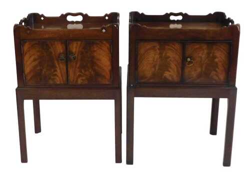A pair of George III style mahogany bedside cabinets, each with a raised gallery above two...