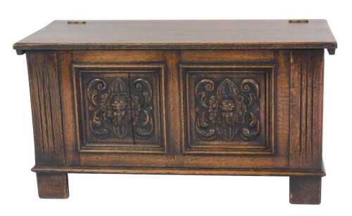 An oak chest, the hinged top enclosing a vacant interior, the panelled front carved with masks,...