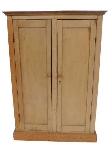 A stripped pine two door cupboard, with a moulded cornice and a plinth, 129cm high, 88.5cm wide,...