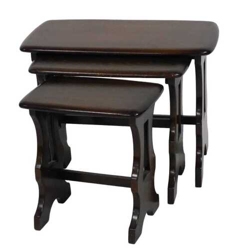 A nest of three Ercol elm tables, each with a rectangular top and pierced end supports, the...