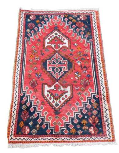 A Caucasian rug, with a central pole medallion, on a red ground, navy blue spandrels, one wide...